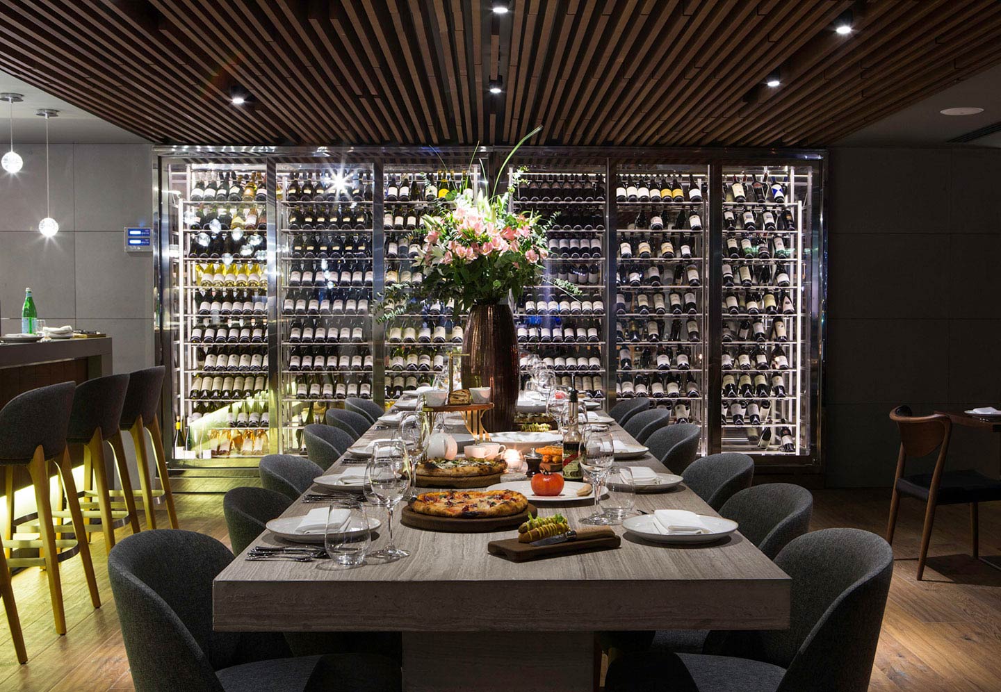 The interior of Marina Social restaurant in Dubai Marina with a long dining table, a beautiful flower arrangement and stacks of bottled grape